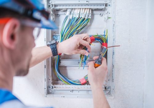 Caucasian Electric Technician in His 30s Installing Electrical System Inside Newly Remodeled Apartment.